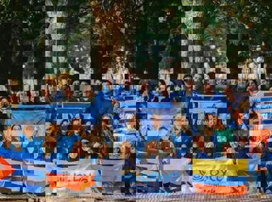 A diverse crowd of people celebrating at a concert, raising their hands and cheering.