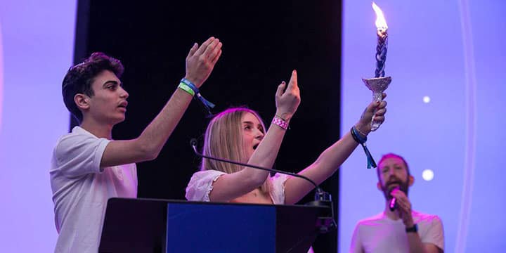 A diverse crowd of people celebrating at a concert, raising their hands and cheering.