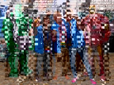 A diverse crowd of people celebrating at a concert, raising their hands and cheering.