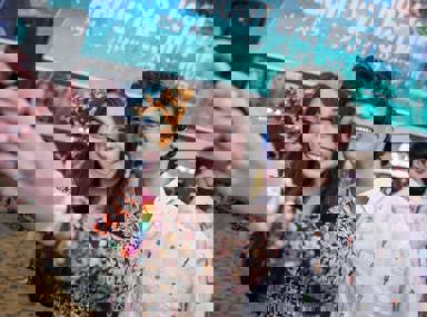 A diverse crowd of people celebrating at a concert, raising their hands and cheering.